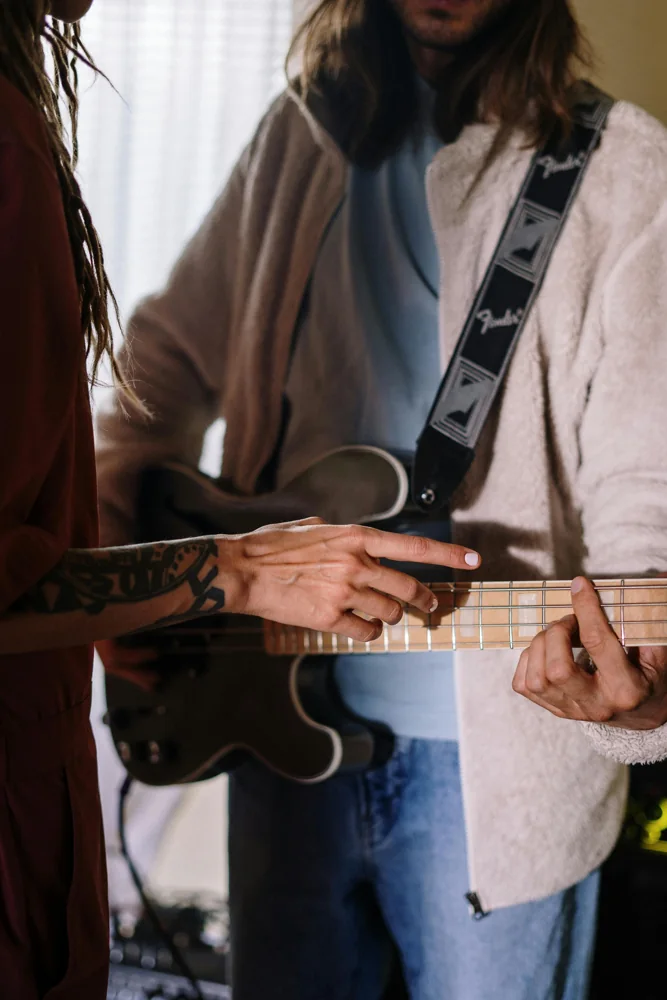 Main posée sur le manche d'une guitare
